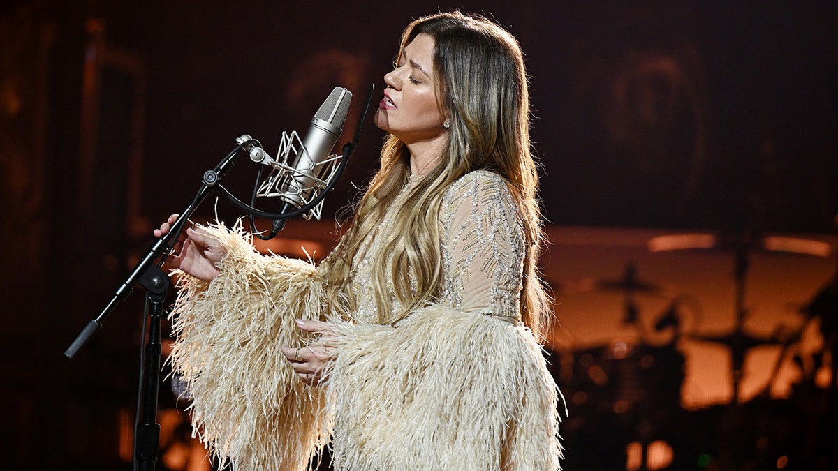 Kelly Clarkson singing into a microphone during her residency