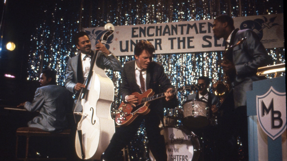 Michael J. Fox playing the guitar on set.