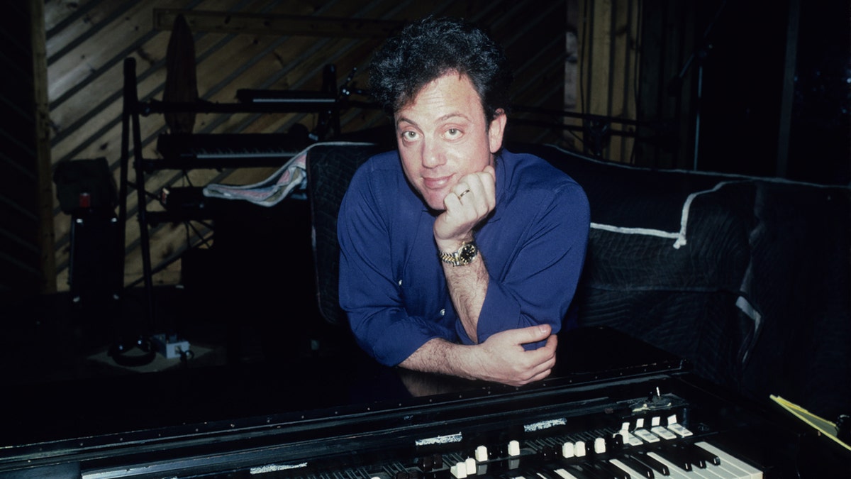 Billy Joel sits in front of a piano