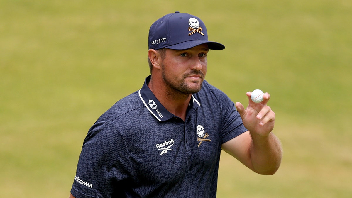Bryson DeChambeau holds up ball
