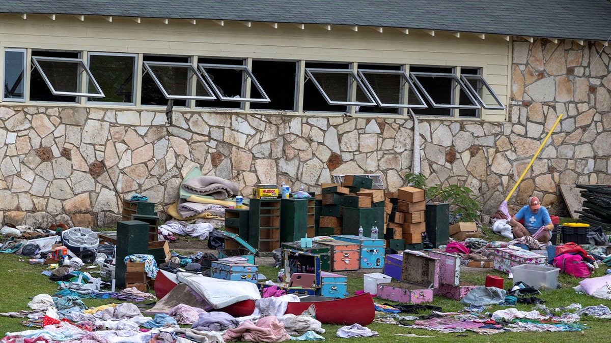 Woman looks at campers' belongings after flood sweeps through Camp Mystic