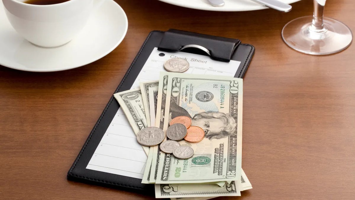 Cash and coins are shown on a restaurant table on top of a check.