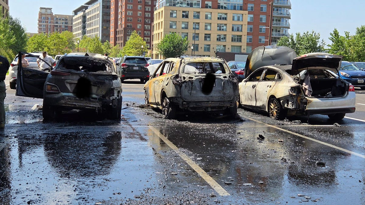 Three charred vehicles in a parking lot