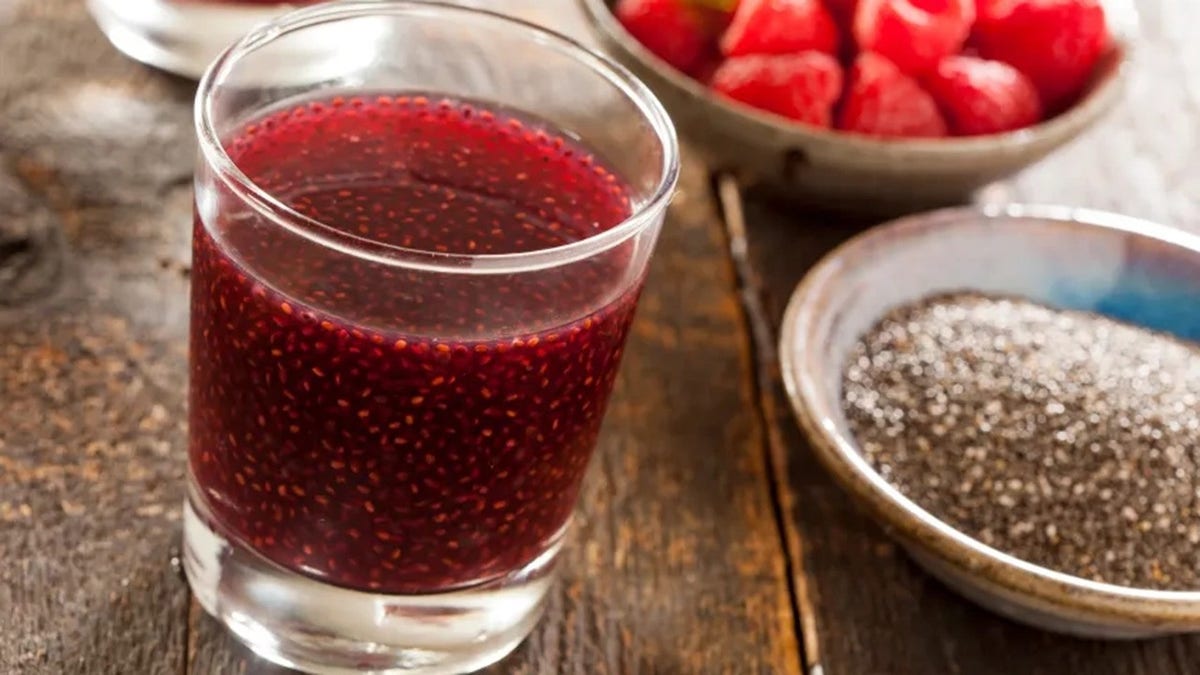 Red chia drinks seen with chia seeds and raspberries next to it