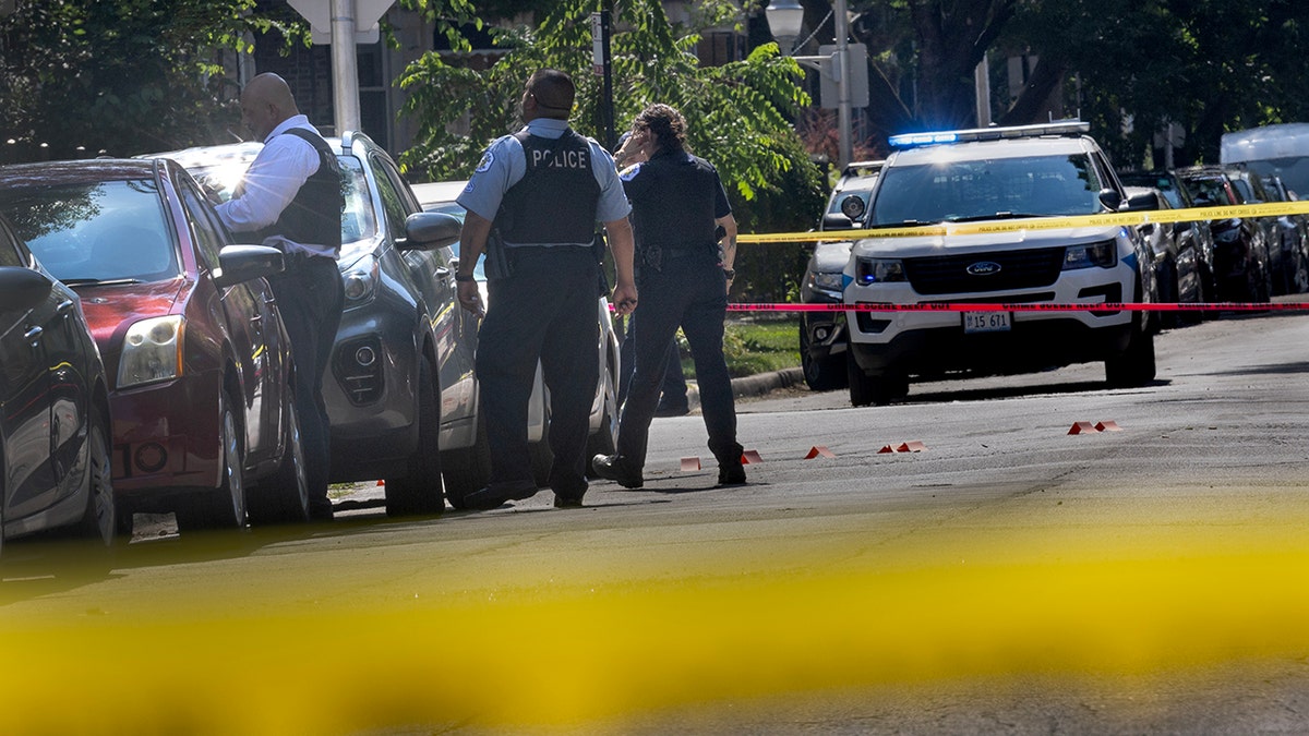Chicago police standing inside a crime scene surrounded by yellow tape.