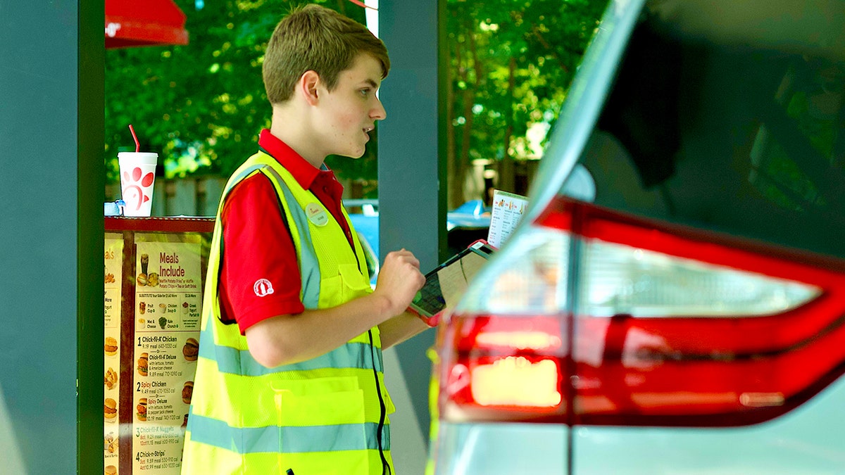 A Chick-fil-A employee takes an order in the drive-thru line.