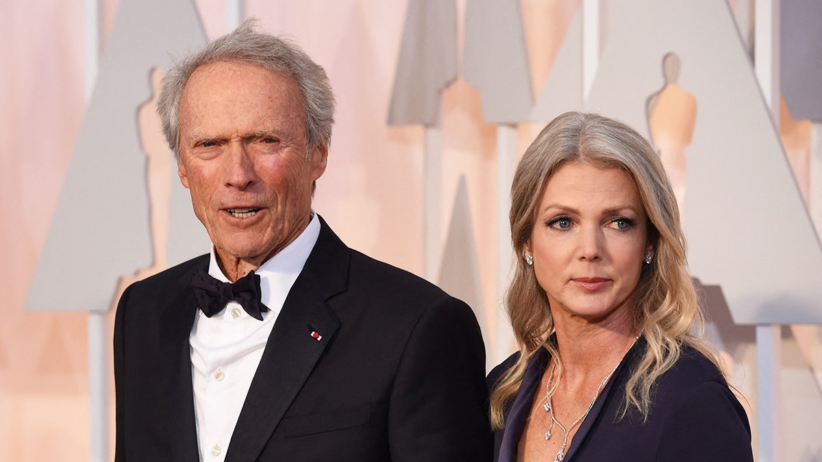 Clint Eastwood in a tux next to a woman wearing a dark dress.