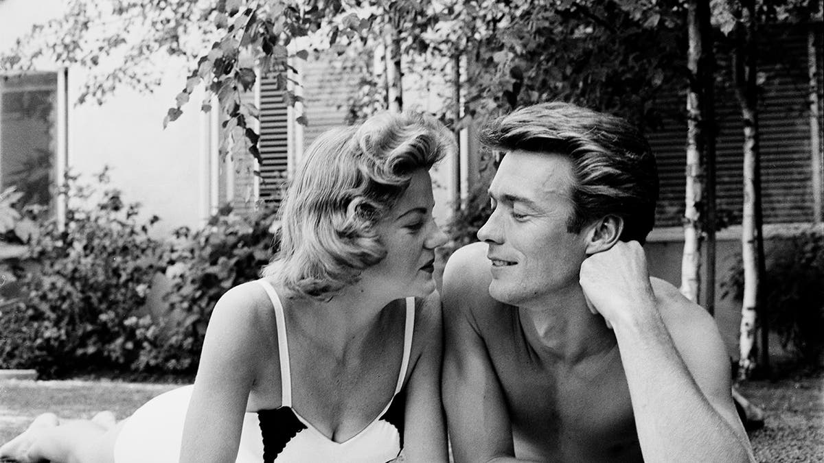 Clint Eastwood admiring Maggie Johnson, who is wearing a swimsuit.