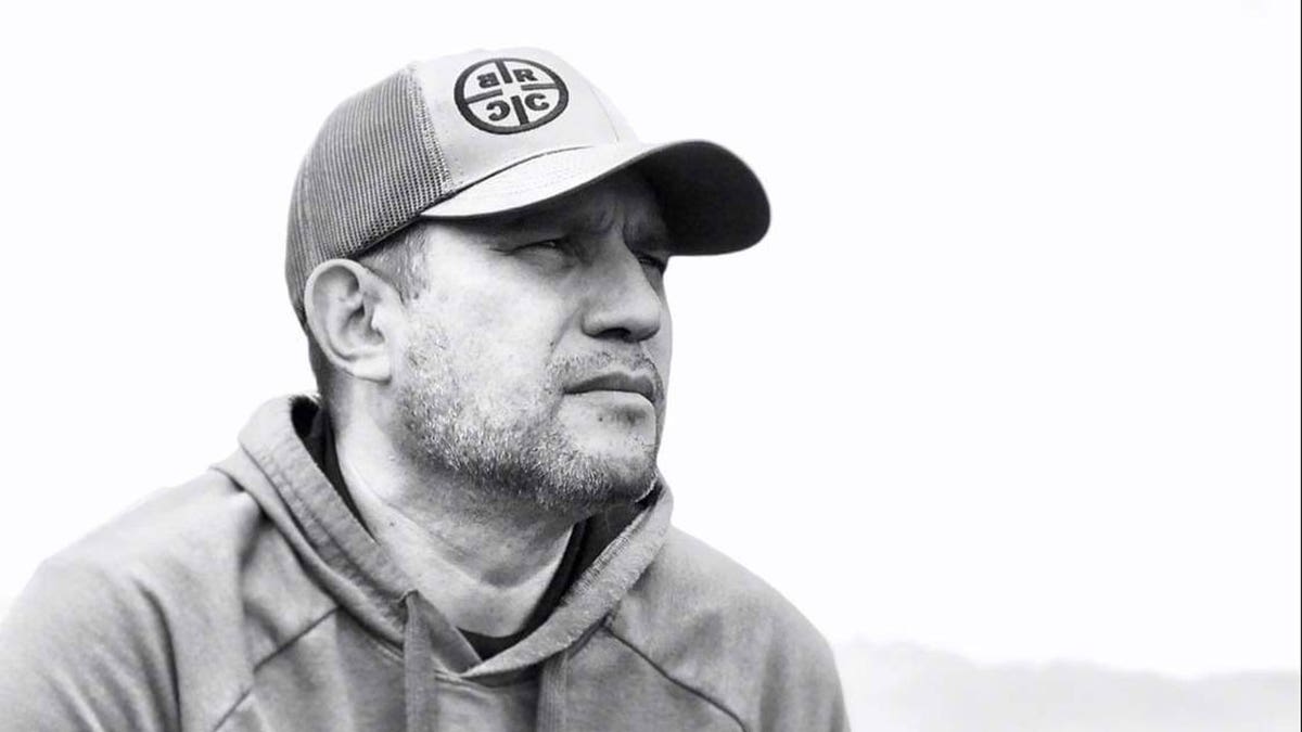 Dan Rivera in a hoodie and hat, looking into the distance