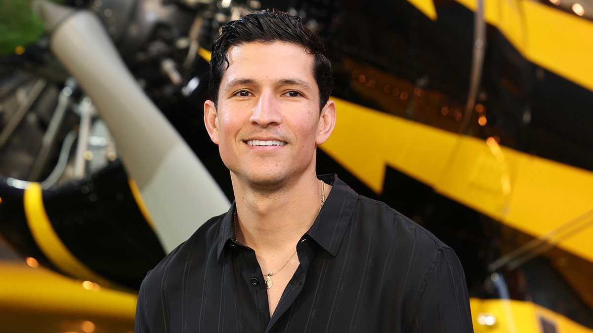 Danny Ramirez wears a black button down shirt.