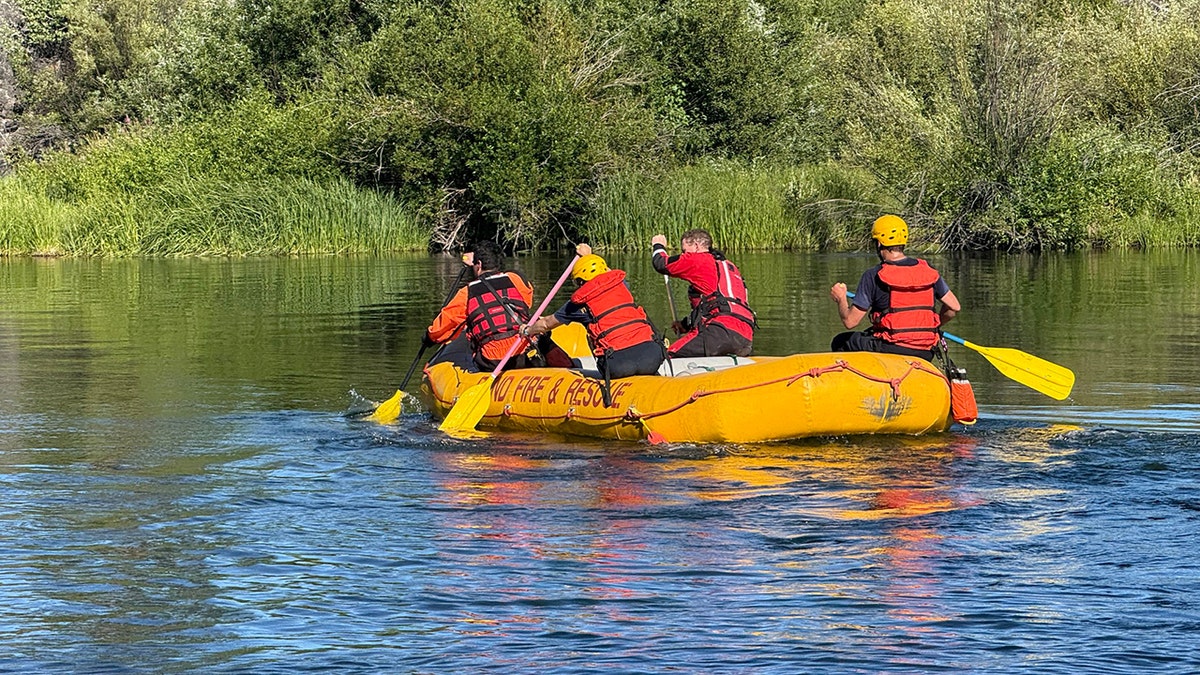 Equipo de búsqueda Remando una balsa amarilla a lo largo del río