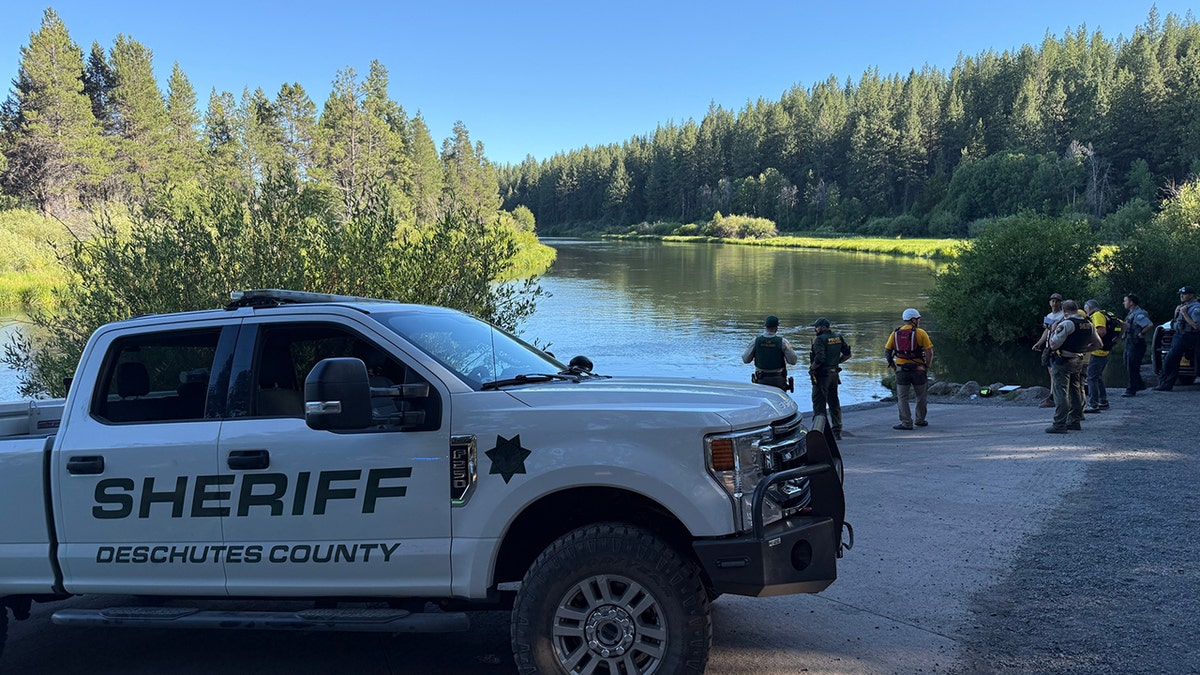sheriff's vehicle and searchers on riverbank