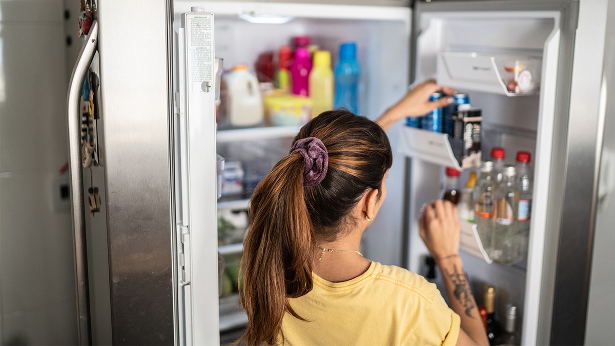 Woman reaching out for drink in fridge