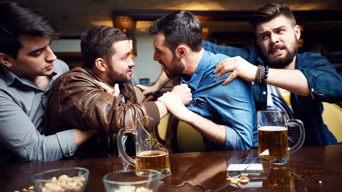Two men seen fighting at bar, with two others trying to pull them apart; drinks and snacks seen on the car.