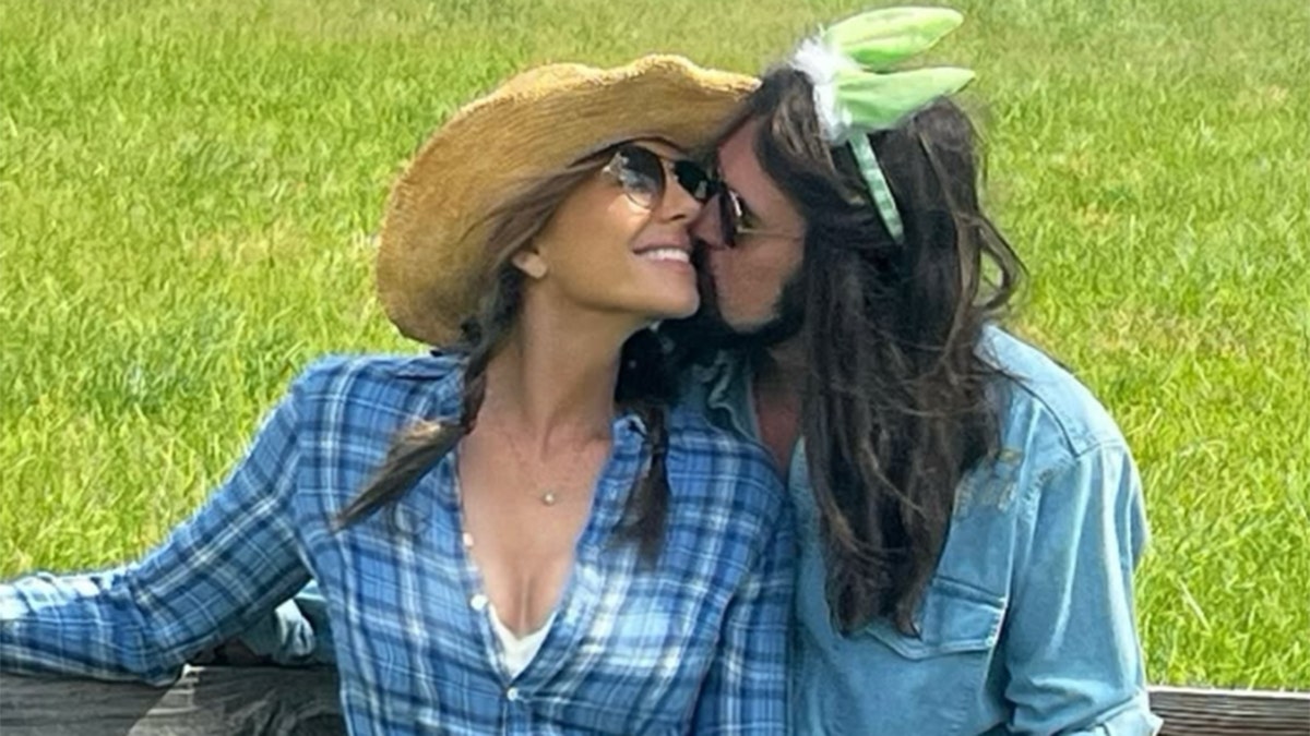 Elizabeth Hurley and Billy Ray Cyrus embracing as he kisses her on the cheek.