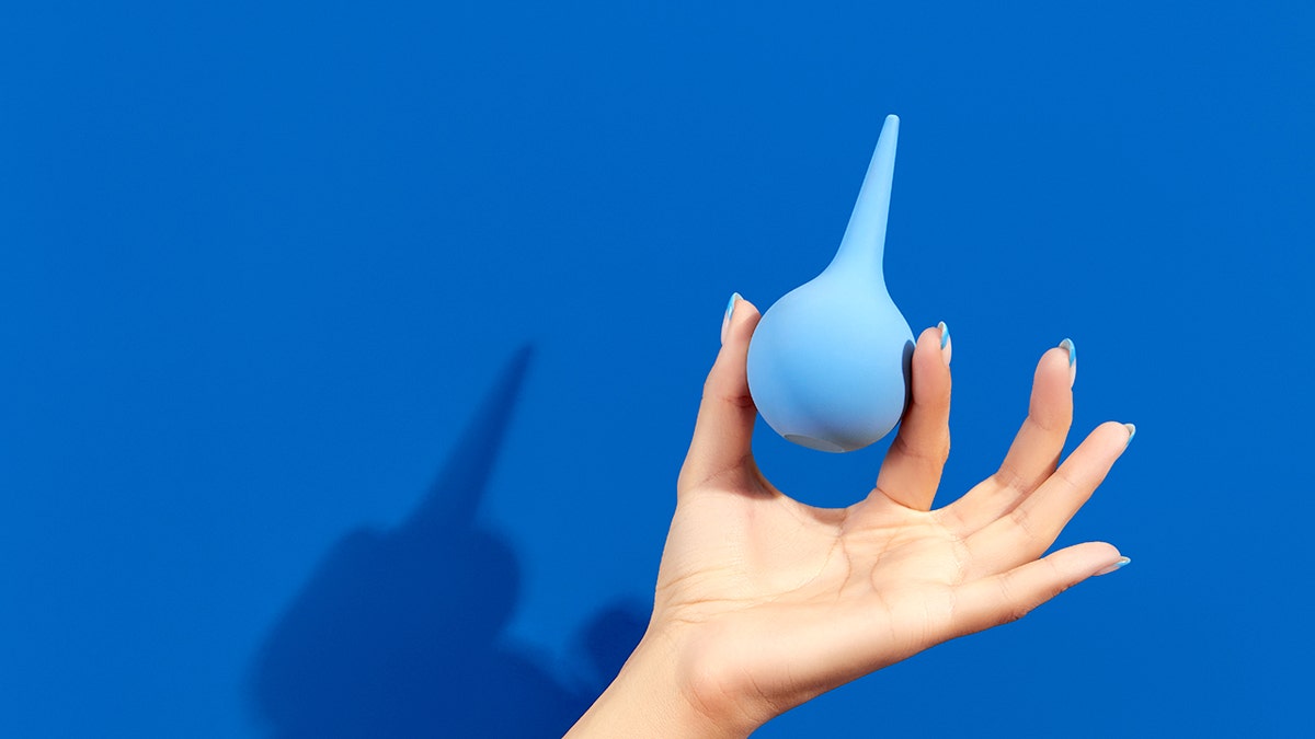 Woman's hand holding an enema device