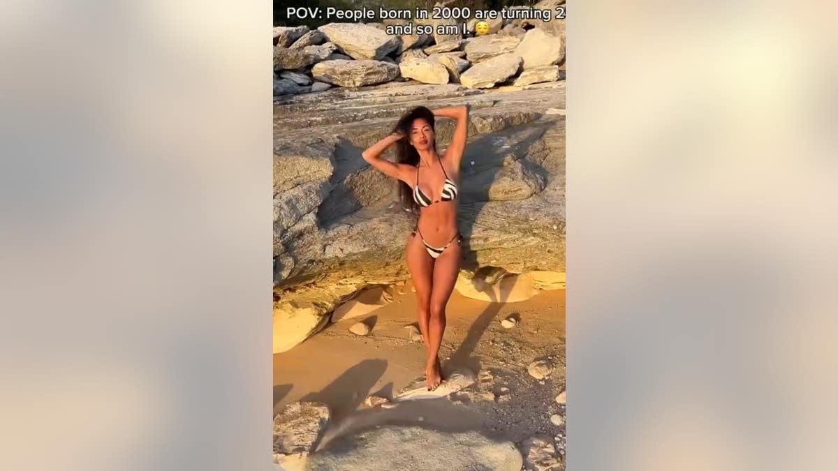 nicole scherzinger poses with her hands on her head on the beach