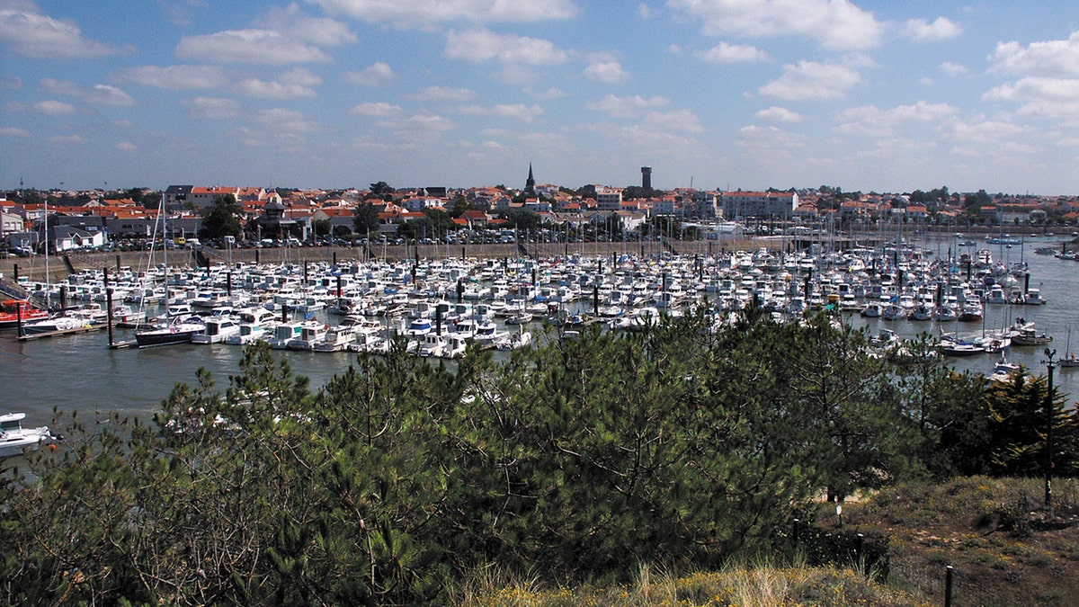This is Les Sables-d'Olonne a seaside holiday resort town in Western France, on the Atlantic Ocean. It is known as the starting point of the Vendee Globe round the world yacht rave. This is a view of the harbour with boats and tourists waling around enjoy