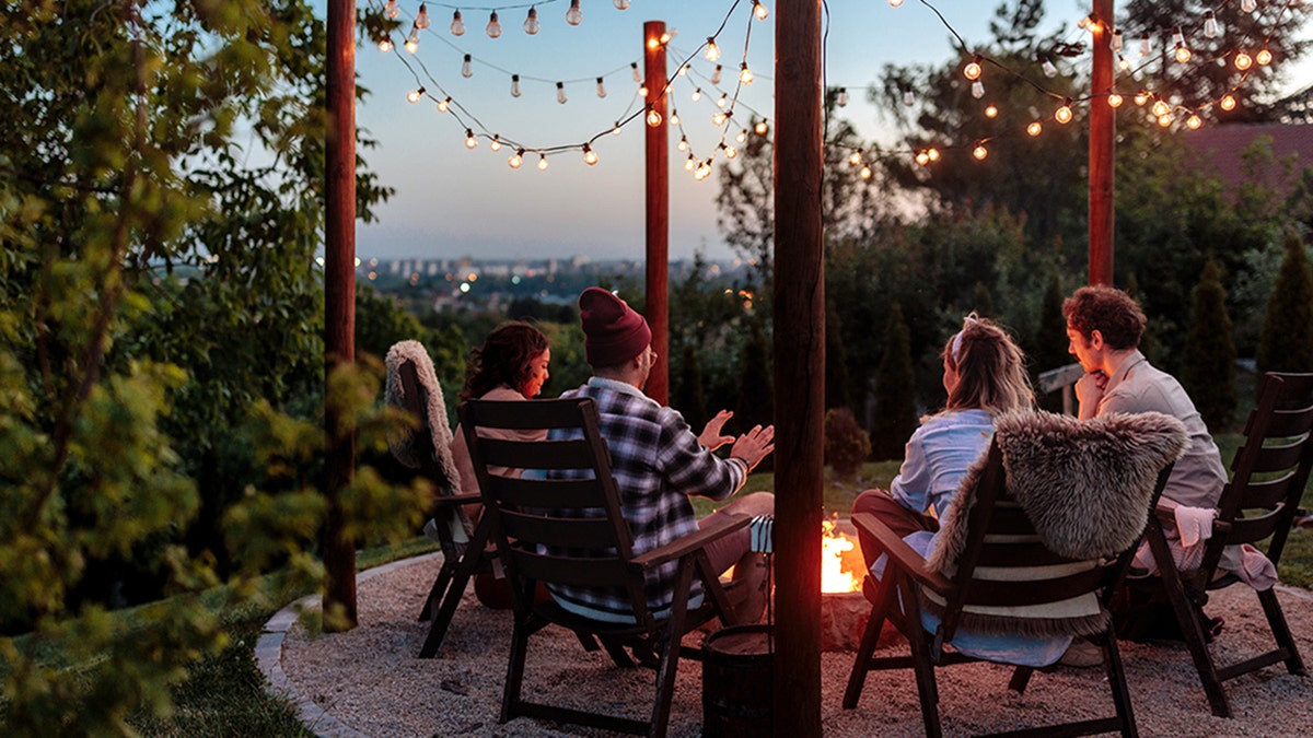 four people sitting around a firepit outside