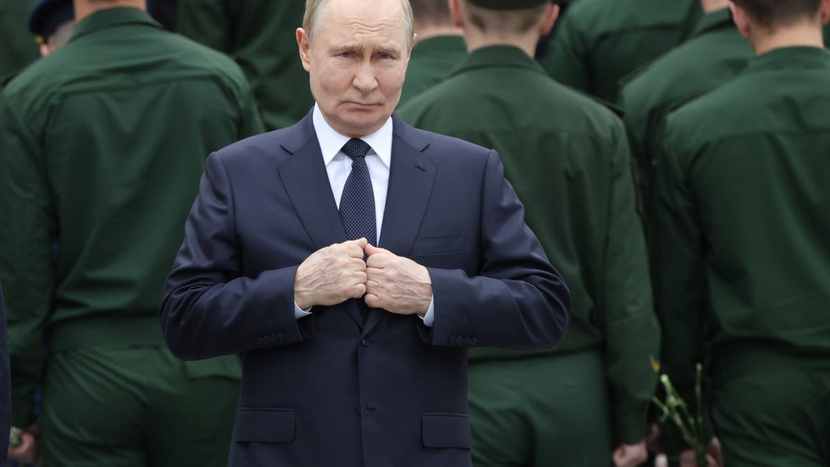 Russian President Vladimir Putin, center, stands during a wreath laying ceremony to the Unknown Soldier's Tomb in the Alexander Garden along the Kremlin wall.