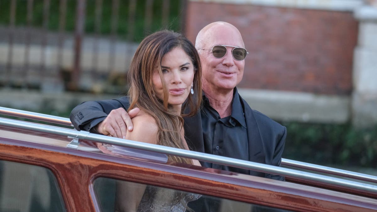 lauren sanchez and jeff bezos wave from a water taxi in venice 