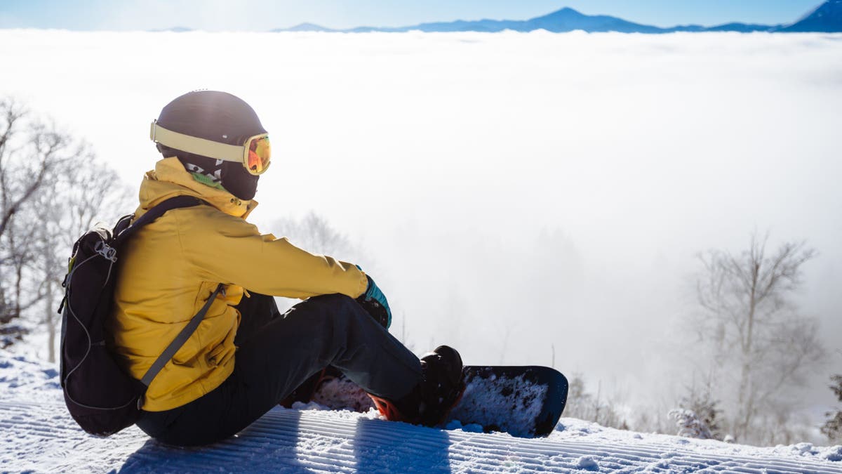 Stock image of snowboarder resting on snowy mountain