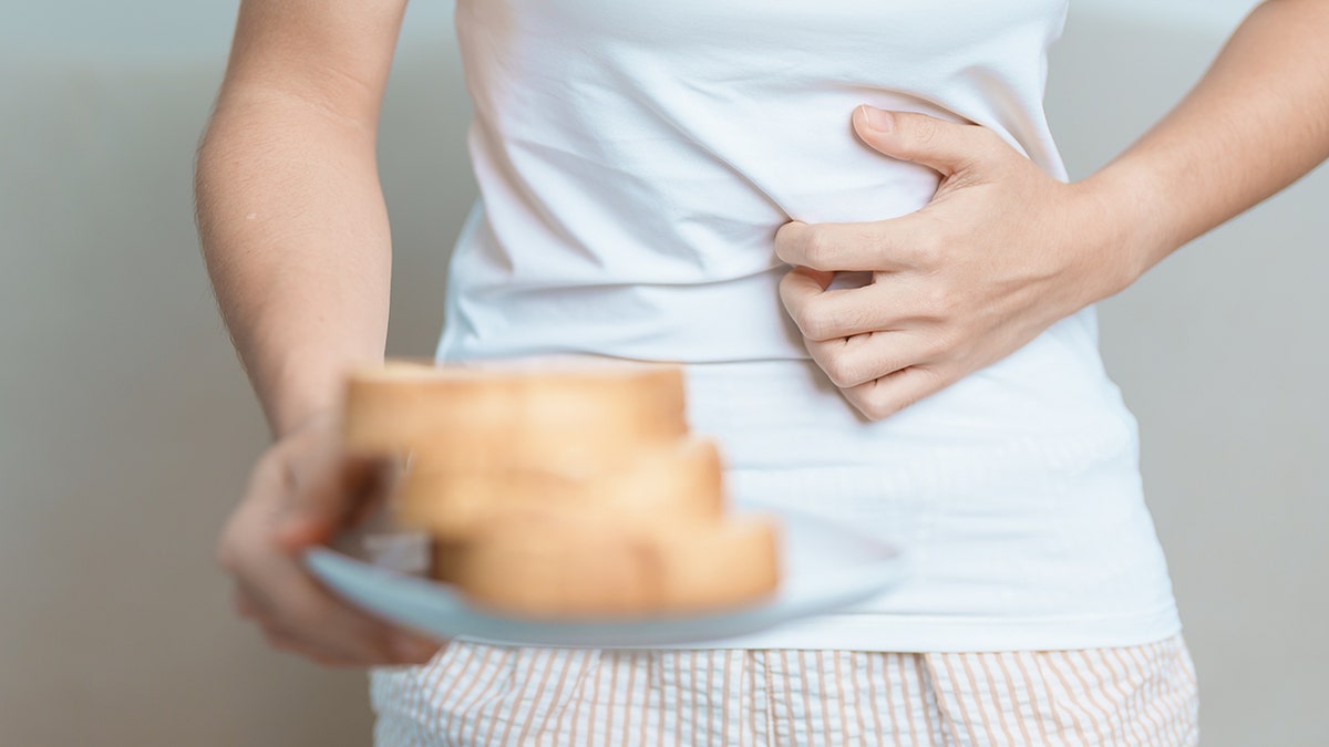 Person with gluten intolerance holding stomach after eating bread