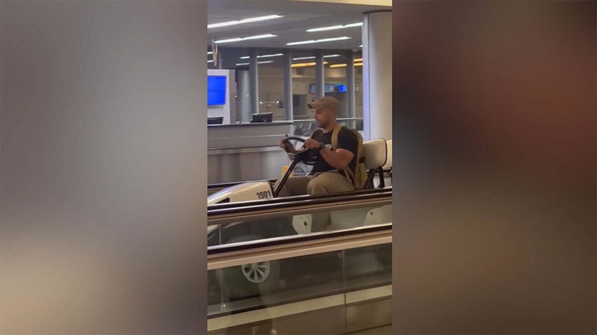 Seorang pria yang mengendarai kereta golf di jalan setapak di bandara