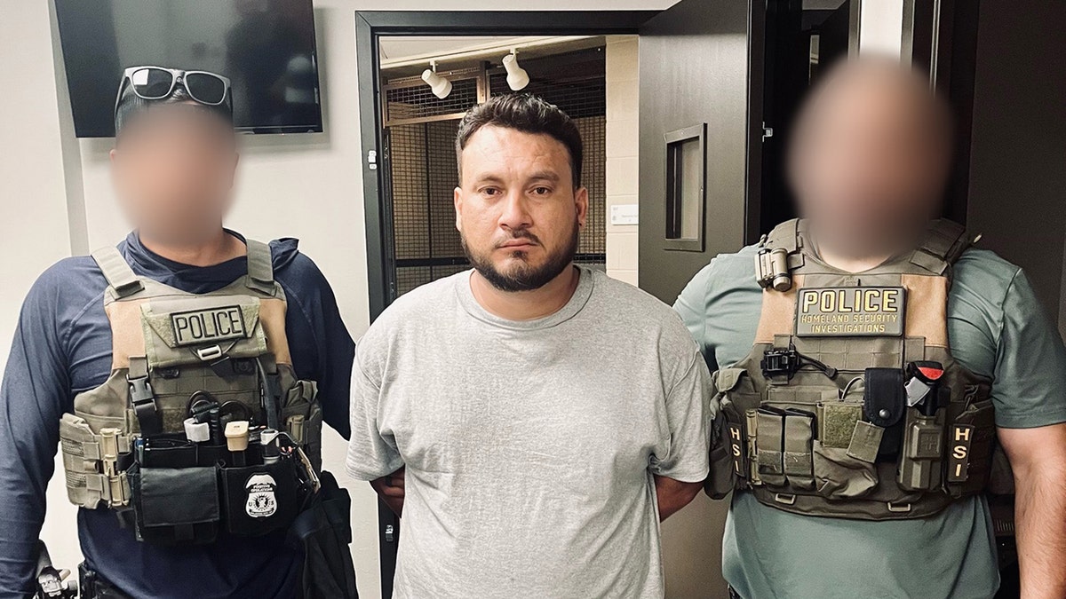 Honduran national held on each arm by ICE agents after being taken into custody