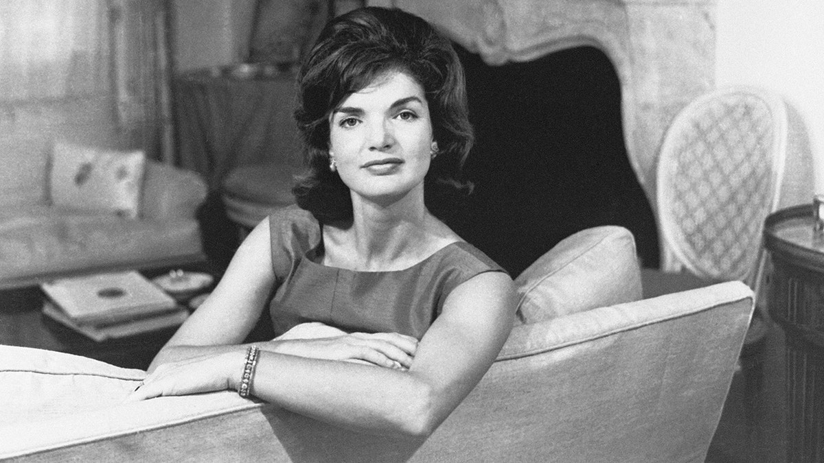 Jackie Kennedy in a poise pose in a living room.