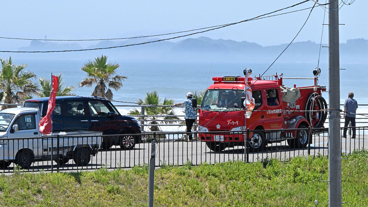 People look at the coastal areas from the highlands after Japan issues evacuation warning