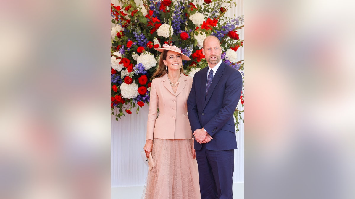 Kate Middleton wearing a pinkish Dior suit opinionated adjacent to Prince William successful a bluish suit pinch flowers down them.