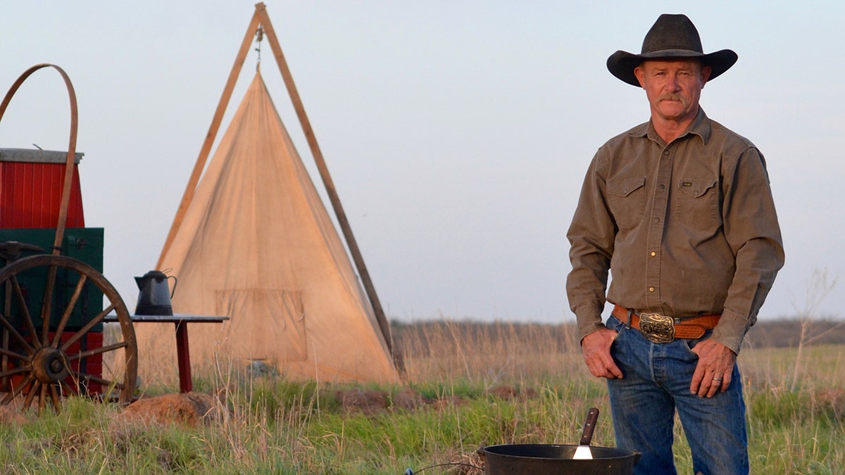 The Kentrollins stand next to a cast iron grill and a tent.