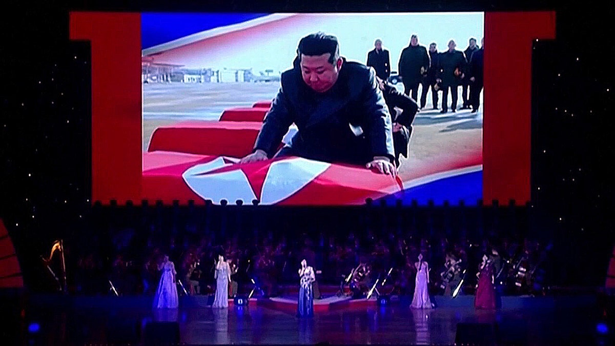 Kim Jong Un on screen mourning over a coffin during a North Korea concert