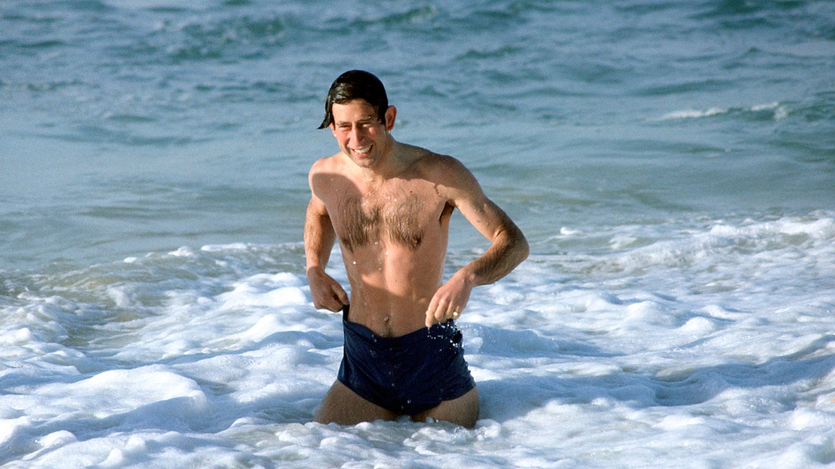 Prince Charles swimming in black trunks.