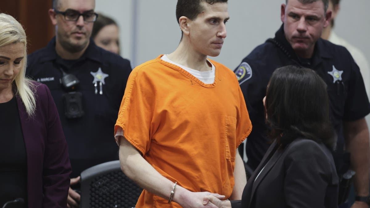 Kohberger in shackles and an orange jail jumpsuit shakes the hand of attorney Elisa Massoth