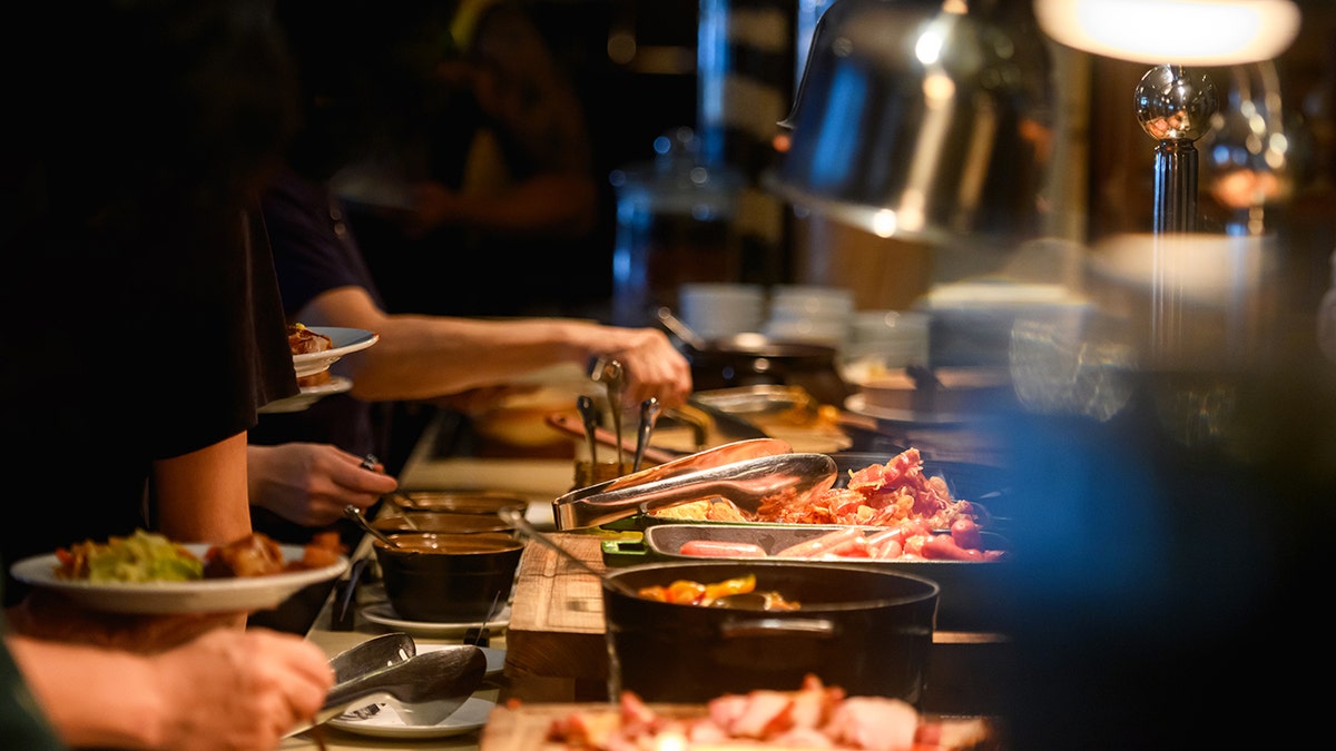Hands holding tongs at buffet