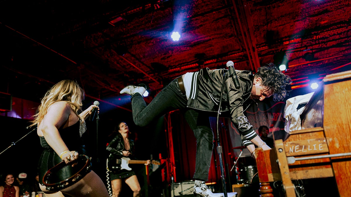 Low cut connie singer playing piano while performing on stage