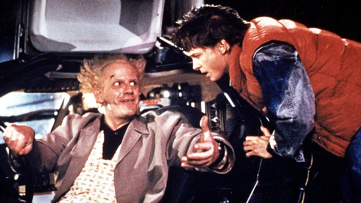 Michael J. Fox speaking to Christopher Lloyd inside a car.