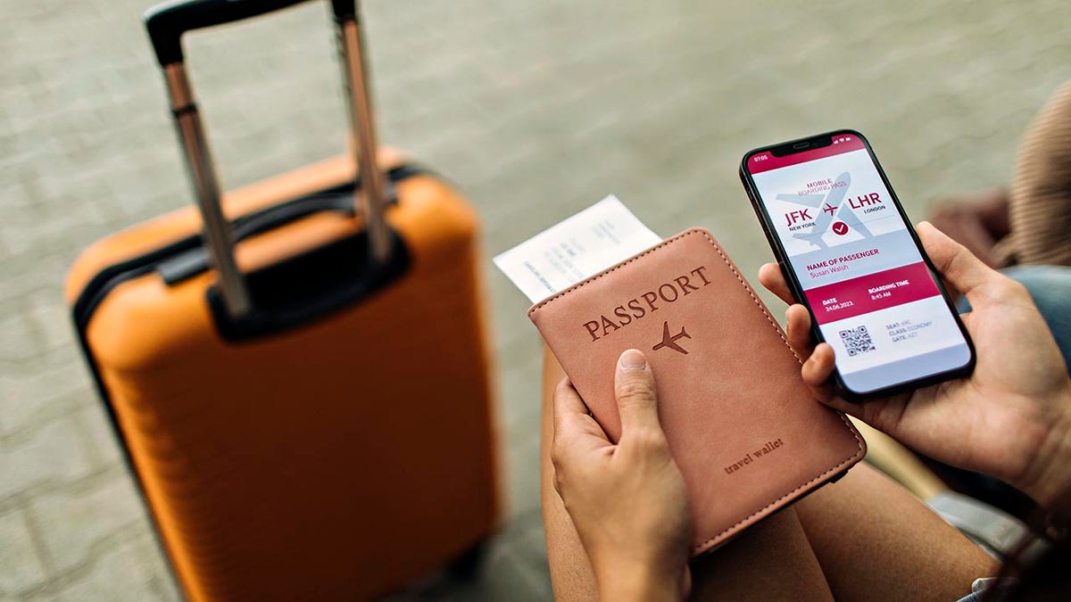 Young female is sitting at the airport holding a passport and a phone while waiting for a flight