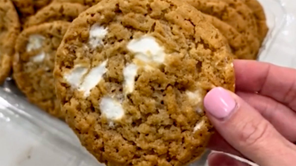 A marshmallow crispy rice cookie from Costco seen up close, being held by TikTok influencer with pink nail polish