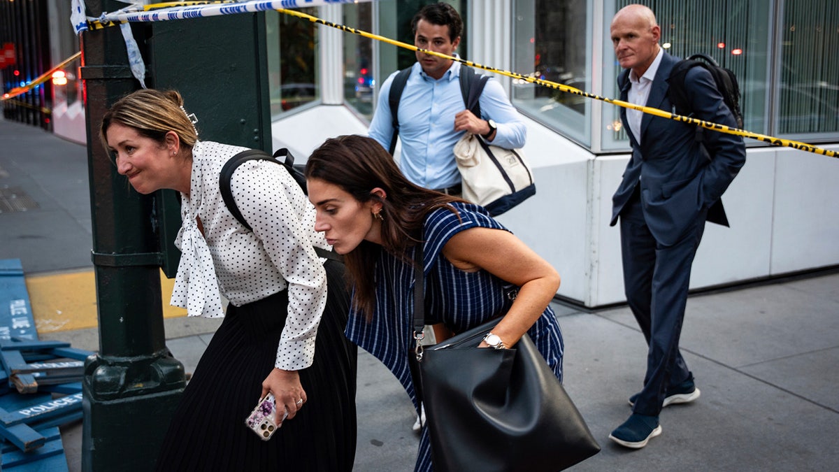 Two women walk by police tape following the Midtown Manhattan shooting