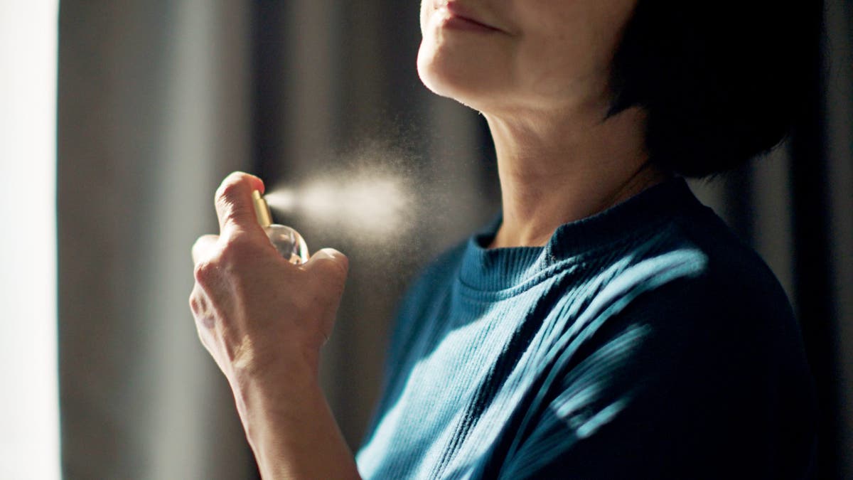 Older woman putting on perfume