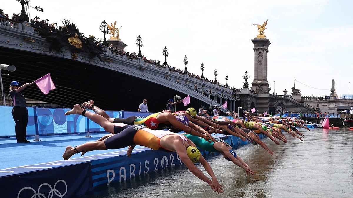 Athletes are shown diving into the Seine to start the swimming stage of the men's individual triathlon at the Paris 2024 Olympic Games in central Paris on July 31, 2024.Â