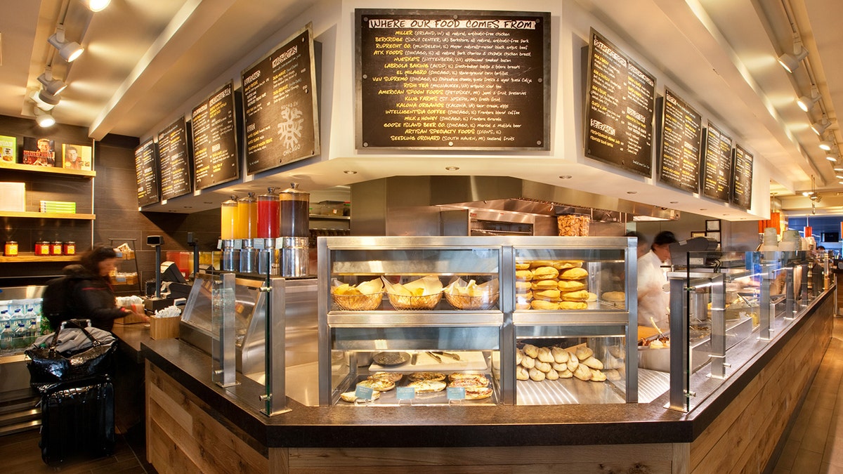 Tortas Frontera restaurant seen at Chicago's O'Hare airport with woman paying and person working behind counter; bread seen in display cases