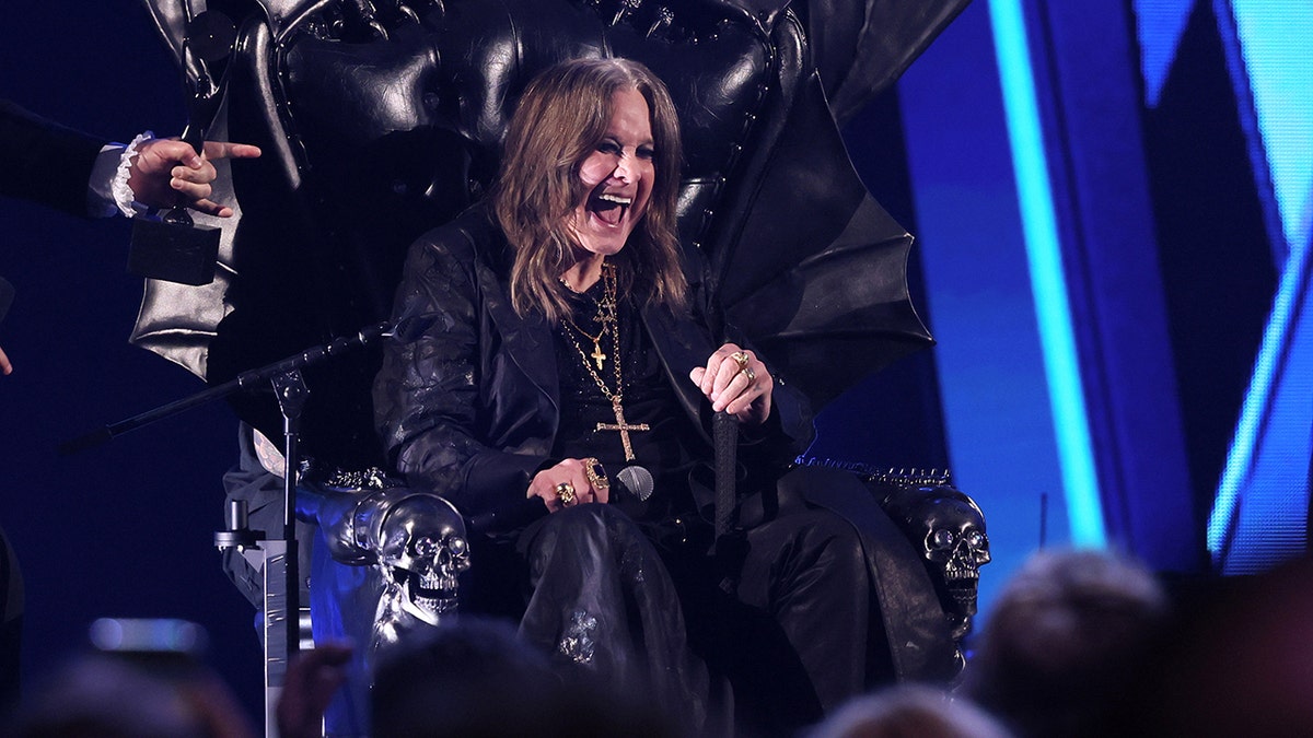 Ozzy Osbourne sitting while holding a microphone