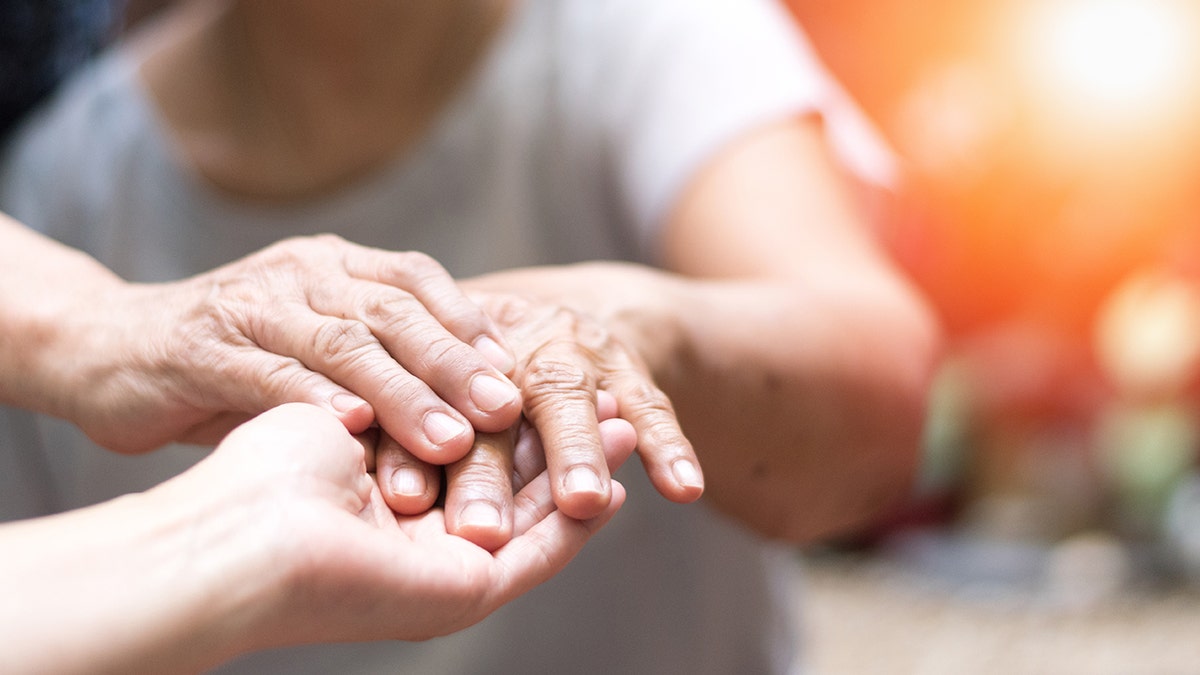 Doctor's hand holding the hand of someone with Parkinson's