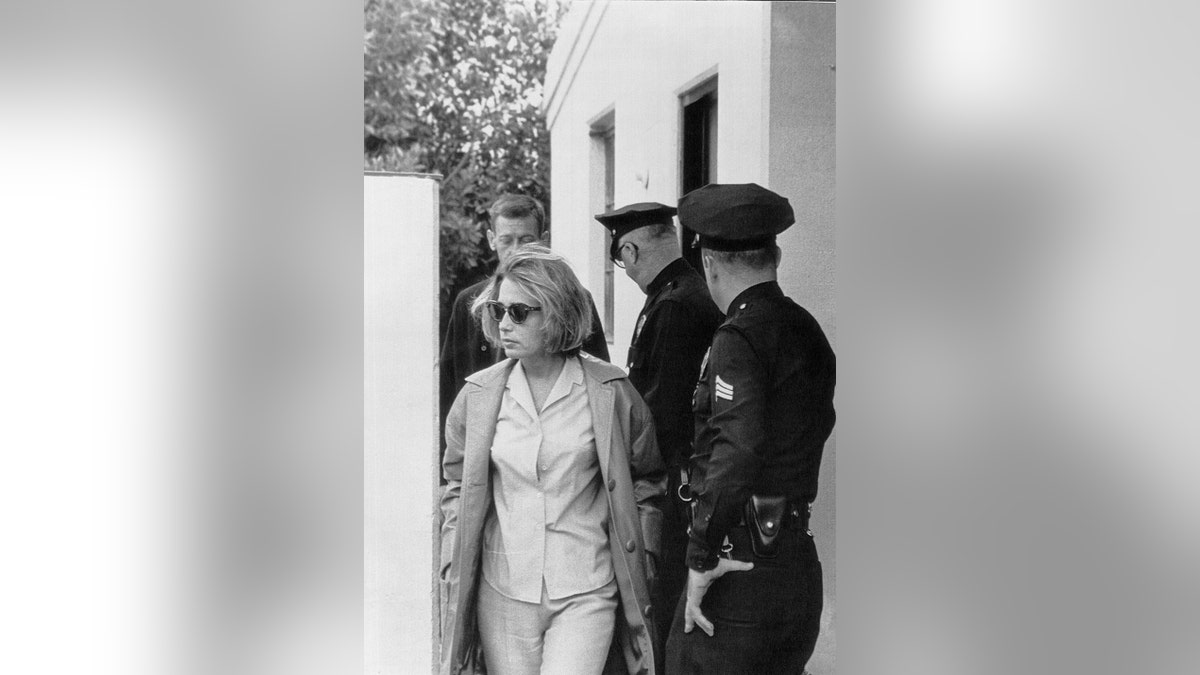 Pat Newcomb wearing sunglasses next to police.