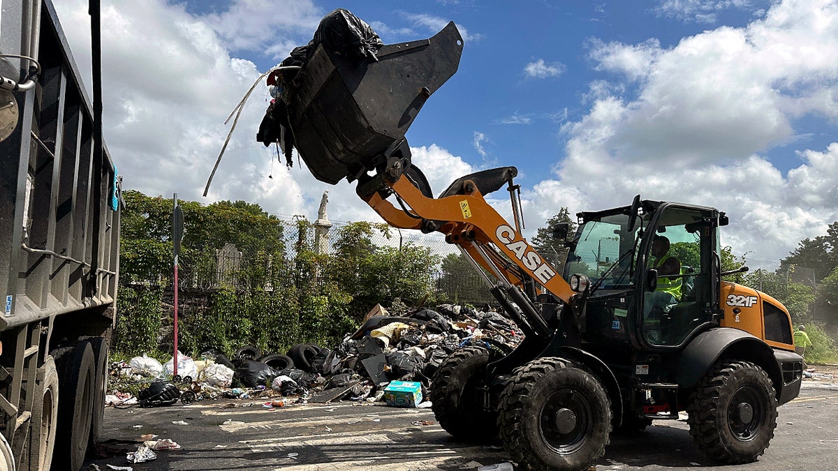 A bulldozer lifts garbage into a dumpster