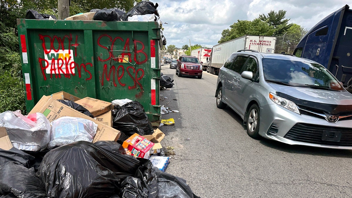 A car drives past a dumpster